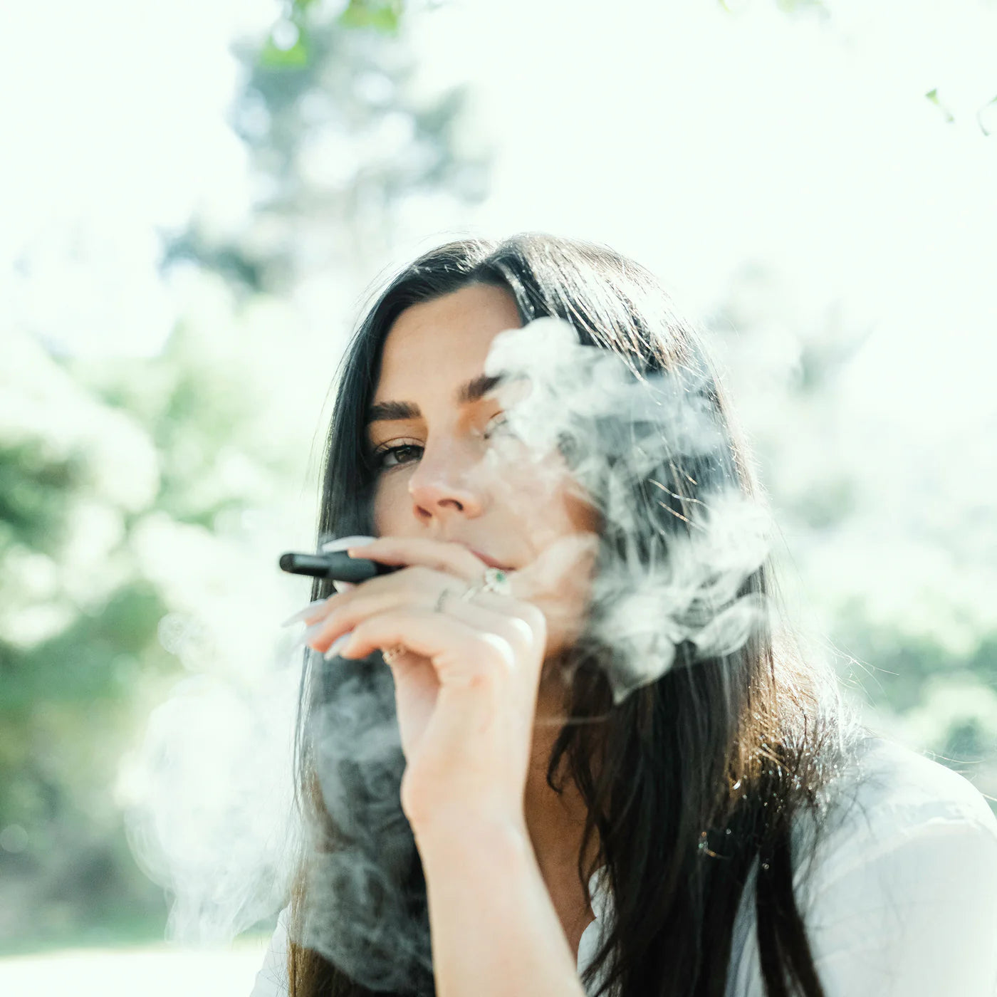 Woman smoking with smoke in a natural setting